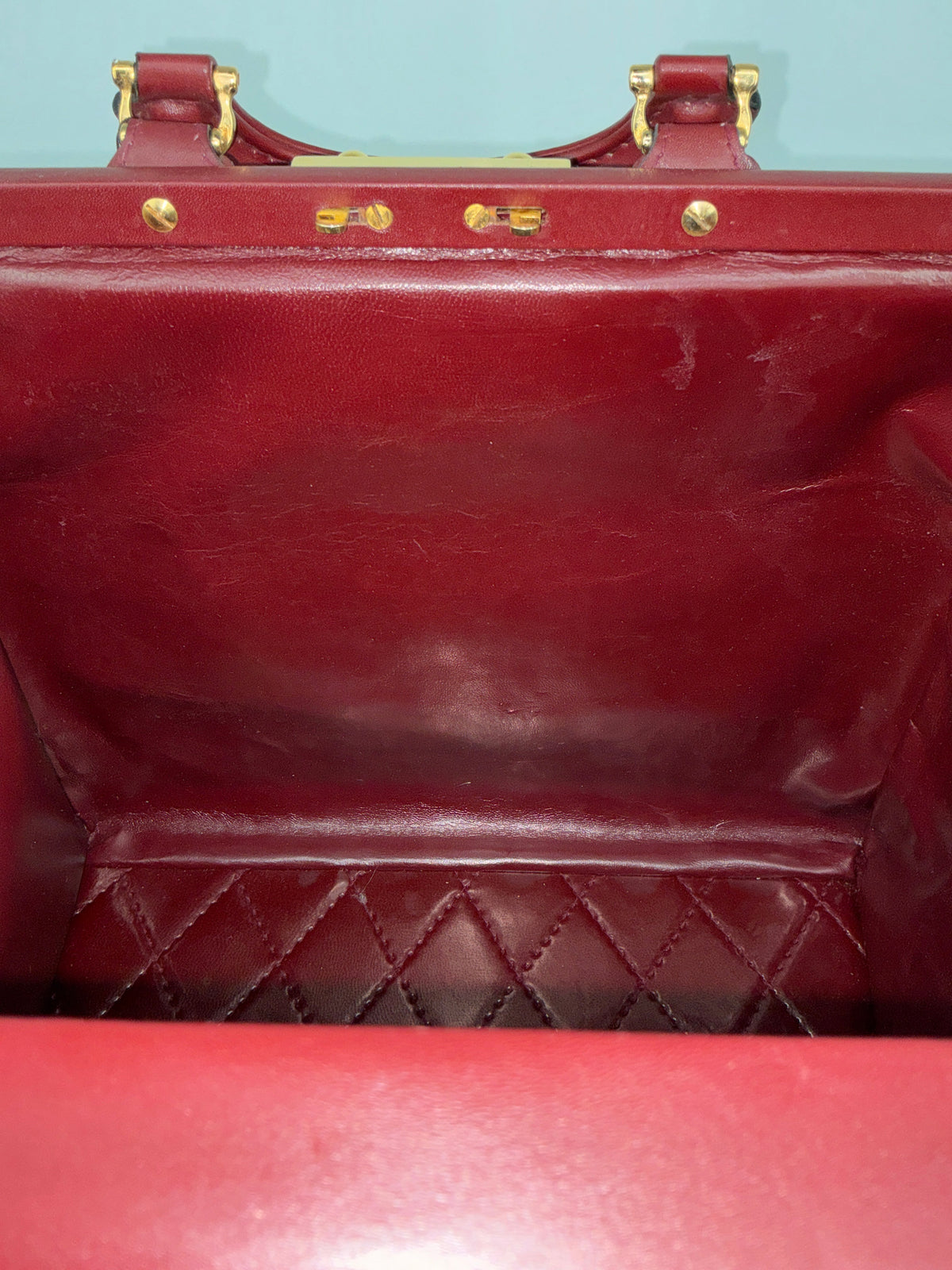 Interior of a vintage House of Melton Les Must de Cartier bordeaux leather travel bag with quilted base and gold hardware